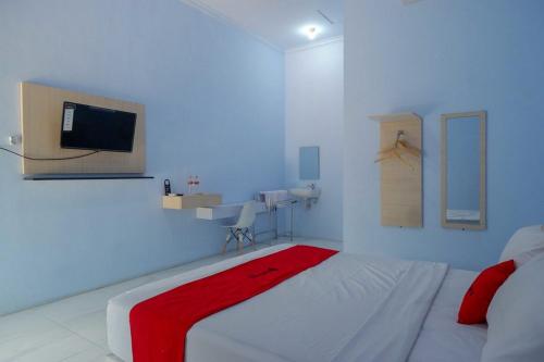 a bedroom with a white bed with a red blanket on it at RedDoorz Syariah near Stasiun Pekalongan 3 in Pekalongan