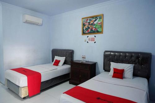 a bedroom with two beds with red and white sheets at RedDoorz Syariah near Stasiun Pekalongan 3 in Pekalongan