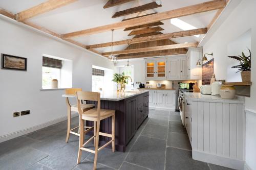 cocina con armarios blancos y vigas de madera en Exceptional cottage with parking, en Blairgowrie