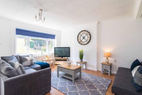 a living room with a couch and a clock on the wall at Modern three bedroom home in Castle Donington in Castle Donington