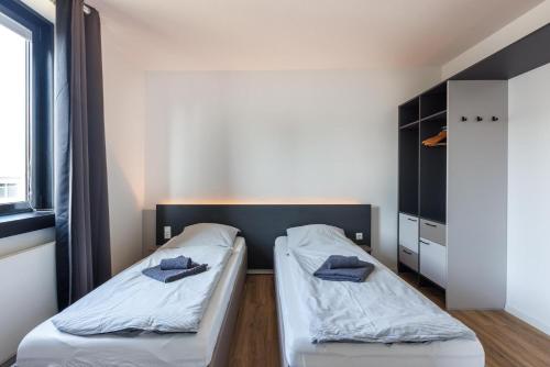 two beds in a room with white sheets and blue pillows at Glück Auf Appartements Düppelstraße in Oberhausen