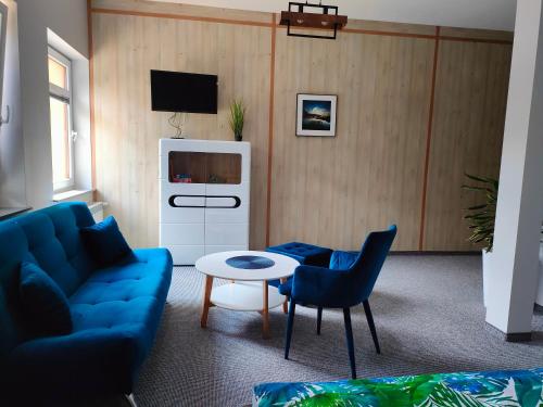 Noclegi Zator Energylandia في Spytkowice: غرفة معيشة مع أريكة زرقاء وتلفزيون