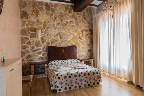 a bedroom with a stone wall with a bed at Casa Rural CUESTA GRANDE in Mota del Cuervo