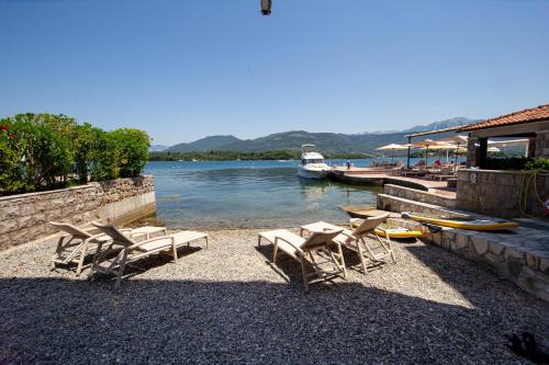 a group of chairs and a boat in the water at Aquamarine House in Tivat