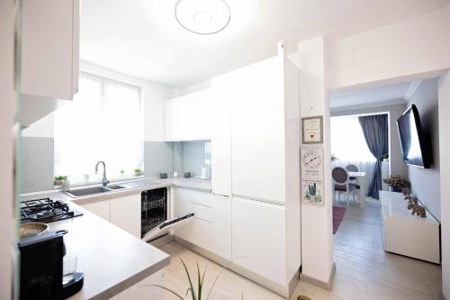 a white kitchen with a sink and a stove at Joyful apartment in Timişoara