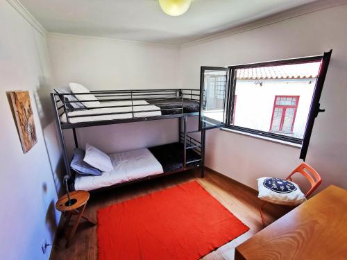 a room with two bunk beds and a red rug at Plantier Guesthouse in Figueira de Castelo Rodrigo