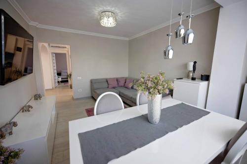 a living room with a table with a vase of flowers at Joyful apartment in Timişoara