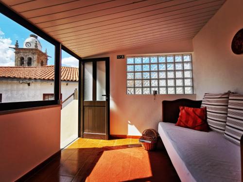 Cette chambre comprend un lit et une fenêtre avec une tour d'horloge. dans l'établissement Saborearia Guesthouse, à Figueira de Castelo Rodrigo
