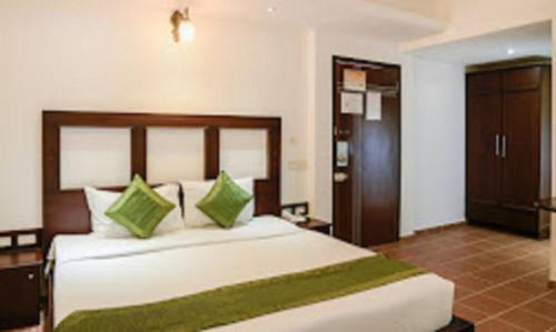 a bedroom with a large white bed with green pillows at Hotel Bright Heritage in Cochin