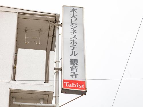 a sign on the side of a building at Tabist Motodai Business Hotel Kanonji in Kanonji