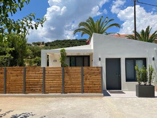 a white house with a wooden fence at Andromahi Apartments & Suite in Laganas