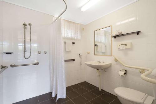 a bathroom with a shower and a toilet and a sink at Merimbula Sapphire Motel in Merimbula