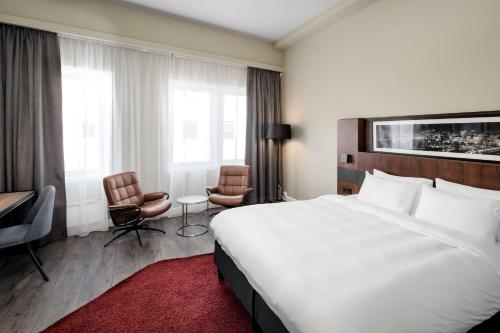a hotel room with a large bed and two chairs at Radisson Blu Hotel Nydalen, Oslo in Oslo