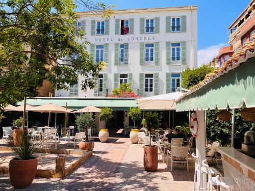 a hotel with tables and chairs in front of a building at Hôtel De Londres in Menton