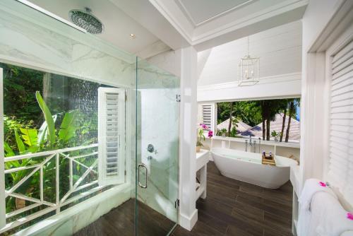 a bathroom with a shower and a tub and a sink at Round Hill Hotel & Villas in Montego Bay