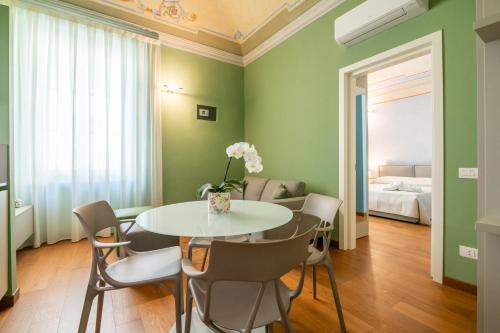 comedor con paredes verdes, mesa y sillas en La Suite del Borghetto, en Pisa