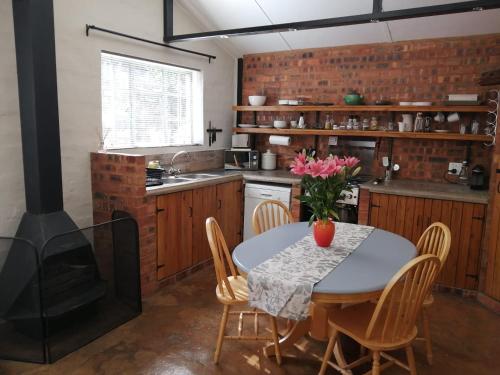 eine Küche mit einem Tisch, Stühlen und einem Herd in der Unterkunft Wild Olive Cottage in Hartbeespoort in Pretoria