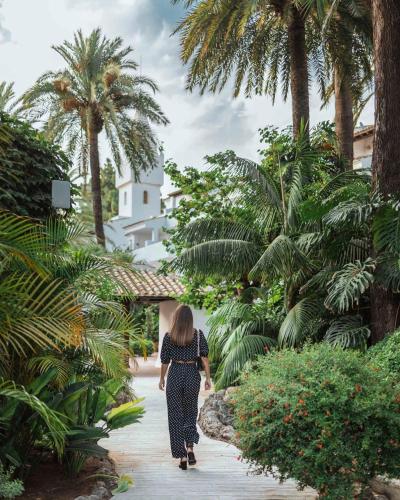 a woman walking down a walkway through a garden at Puente Romano Marbella in Marbella