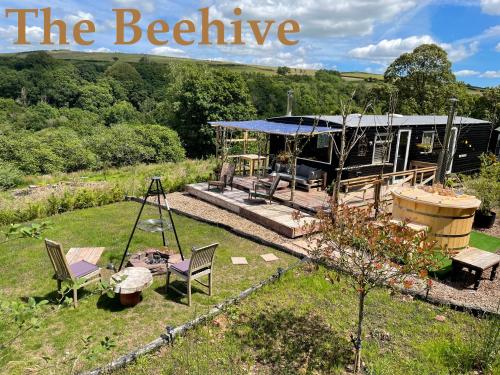 a garden with chairs and a house in the background at The Good Life Wales with Hot tubs in Llywel