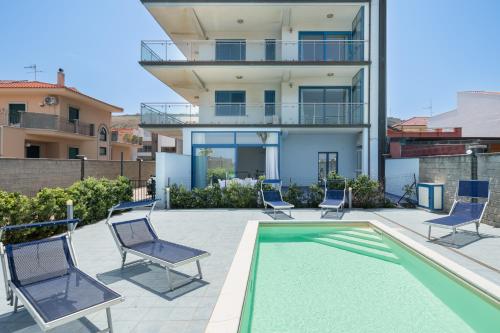 a house with a swimming pool with chairs and a house at Terraces d'Orlando - Family Apartments with Sea View and Pool in Capo dʼOrlando