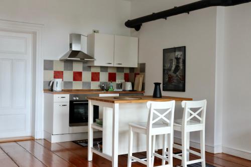 a kitchen with white cabinets and a counter with chairs at Gutshaus Alt Vorwerk in Boddin