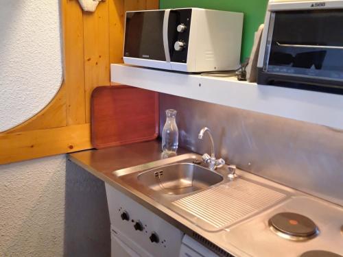 un comptoir de cuisine avec un évier et un micro-ondes dans l'établissement Studio lumineux au centre, balcon, proche pistes, wifi inclus - FR-1-346-420, à Arc 1800