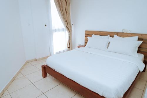 a bed with white sheets and pillows in a room at RESIDENCE OLIE OFFICIEL in Douala