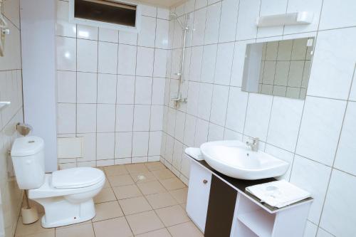 a white bathroom with a toilet and a sink at RESIDENCE OLIE OFFICIEL in Douala