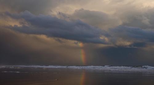 a rainbow in the sky over a beach with the ocean at La Casa de Oti playa Mazagón vistas al mar in Mazagón