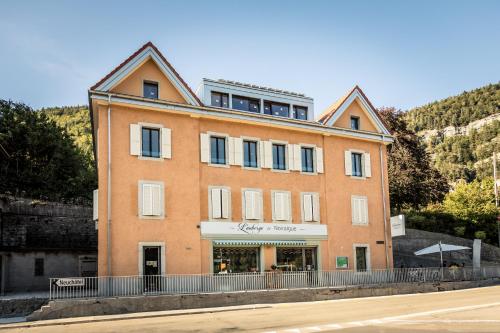 a large orange building on the side of a street at L'auberge de Noiraigue in Noiraigue