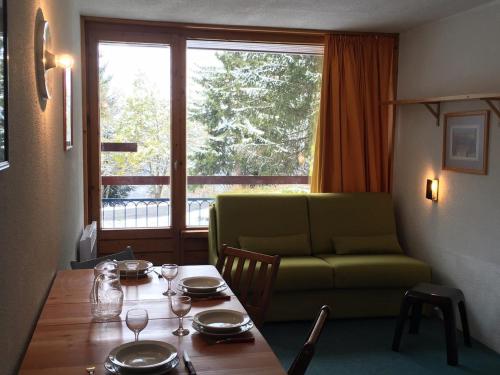 - un salon avec une table et un canapé vert dans l'établissement Studio cosy · pied des pistes · balcon · 5 pers. - FR-1-346-491, à Arc 1800