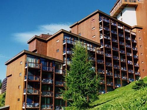 un grand bâtiment avec un arbre devant dans l'établissement Studio cabine 4 pers, proche centre, balcon - FR-1-346-457, à Arc 1800