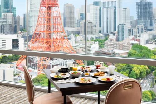 a table with food on a balcony with a view of a city at The Prince Park Tower Tokyo in Tokyo