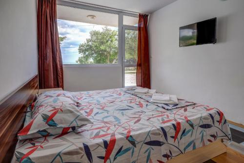 1 dormitorio con cama con edredón y ventana en Saint George Hotel 2, en Kavarna