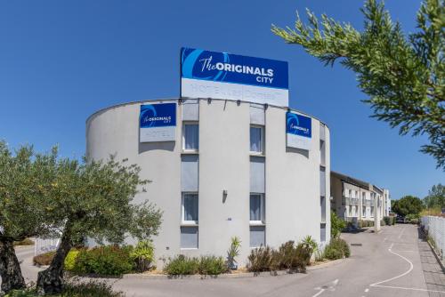 a building with a sign on top of it at The Originals City, Hôtel Les Dômes, Perpignan Sud Saleilles in Perpignan