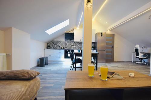 a kitchen and living room with a wooden table and two glasses at Apartamenty Żołnierska 31 - Apartament nr 1 in Bytom