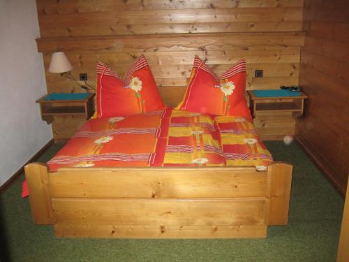 een slaapkamer met een houten bed met rode kussens bij Apartment Hölzlbauer in Krimml