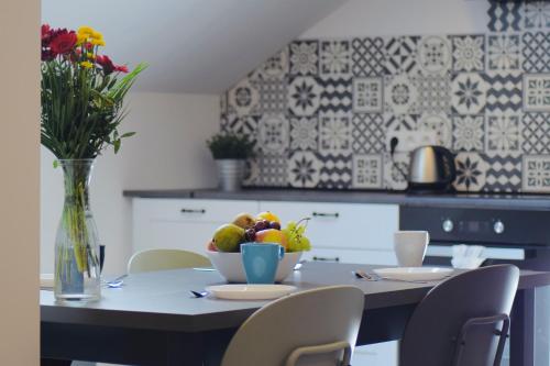 a table with a bowl of fruit and a vase of flowers at Apartamenty Żołnierska 31 - Apartament nr 1 in Bytom