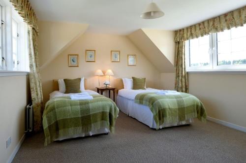 two beds in a room with two windows at Bruntlands Steading in Fochabers