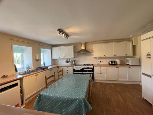 a kitchen with white cabinets and a table in it at Bruntlands Steading in Fochabers