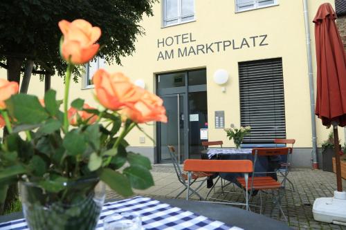 a vase with orange flowers on a table in front of a hotel am mar at Hotel am Marktplatz in Gangkofen