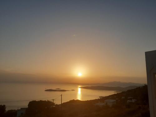 a sunset over the water with the sun in the sky at Aegean Mirror, Andros in Apróvaton