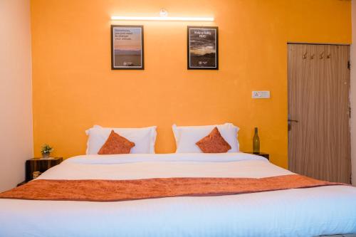 a bedroom with a large white bed with orange walls at SUN 2BHK by Wabi Sabi Stays Steep Uphill walk 5 Mins in Mussoorie