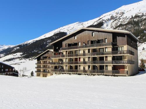 un grand bâtiment dans la neige devant une montagne dans l'établissement Studio cosy pour 2/3 pers., skis aux pieds, proche commerces et services à Val-Cenis - FR-1-508-235, à Lanslebourg-Mont-Cenis