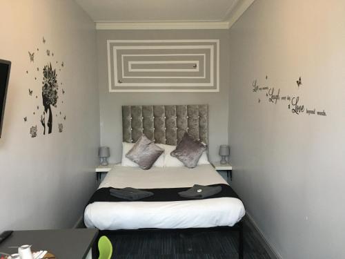 a bedroom with a bed with a headboard and writing on the wall at Queens Guesthouse Manchester in Manchester