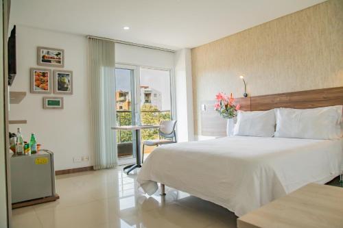 sypialnia z dużym białym łóżkiem i oknem w obiekcie Hotel Estancia Chipichape Cali w mieście Cali