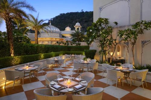 een restaurant met tafels en stoelen op een patio bij The Leela Palace Jaipur in Jaipur