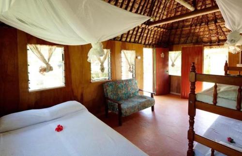 a bedroom with a bed and a chair at Nabua Lodge in Nacula Island