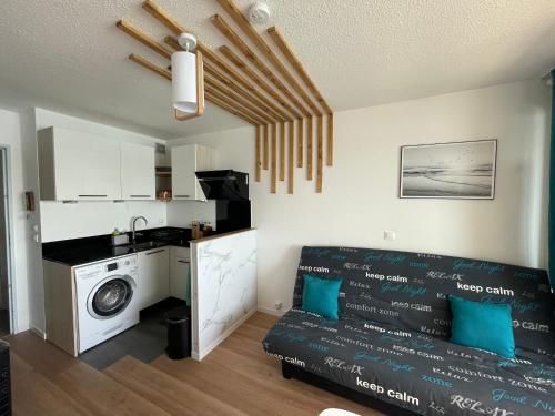 uma sala de estar com um sofá e uma máquina de lavar roupa em Appart en résidence calme avec parking privé em Leucate