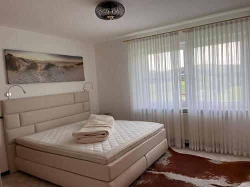 a white bedroom with a bed and a window at Ferienwohnung-Orth-Tor-zum-Sauerland-mit-grosser-Terrasse in Meinerzhagen